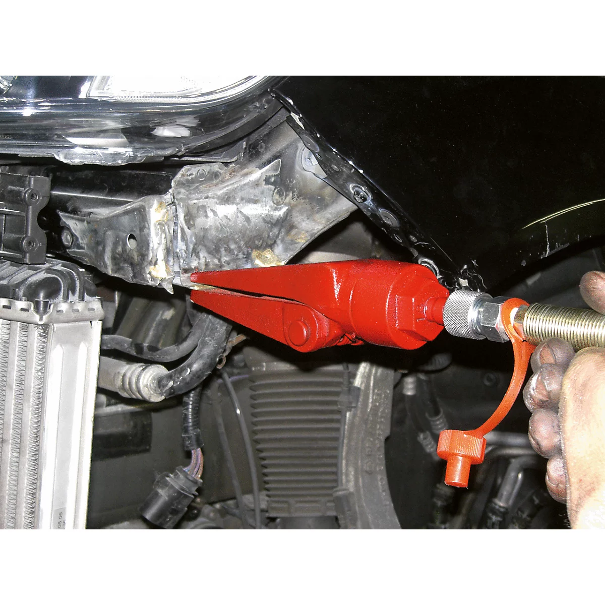 Nahaufnahme eines roten Werkzeugs, das an einem Autoteil eingesetzt wird, um es zu reparieren.